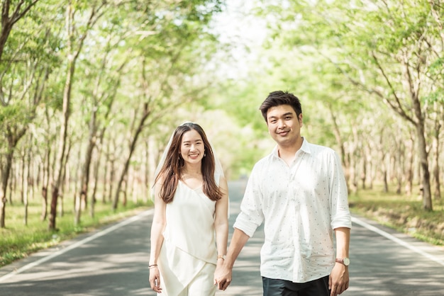 木のアーチと道路上の愛の幸せなアジアカップル