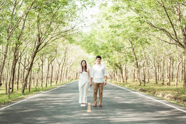 Happy Asian couple in love on road with tree arch