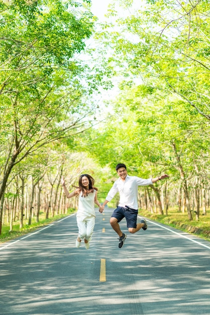 Happy Asian couple in love on road with tree arch