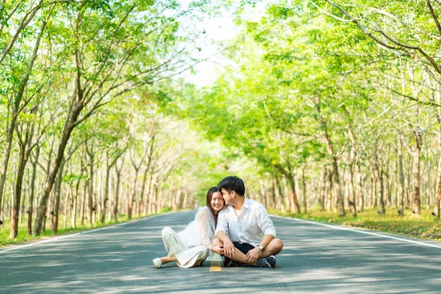 木のアーチと道路上の愛の幸せなアジアカップル