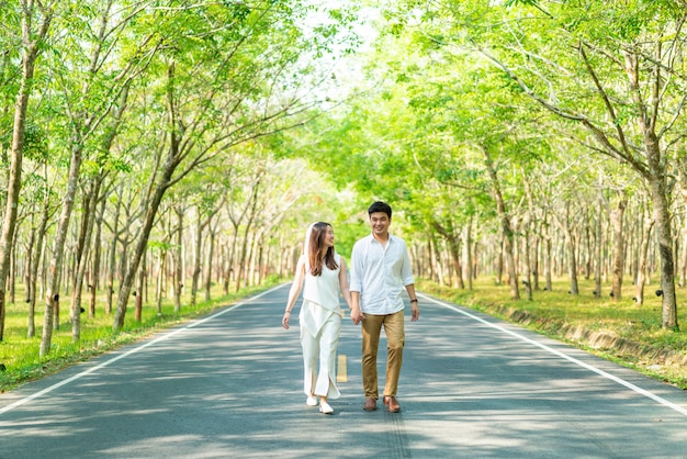 木のアーチと道路上の愛の幸せなアジアカップル