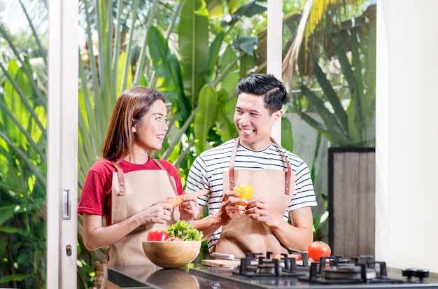 Happy asian couple preparing fresh vegetables for cooking