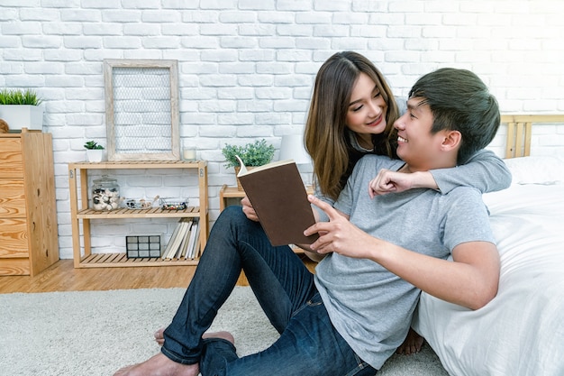 Happy Asian couple reading the book or notebook on the bed