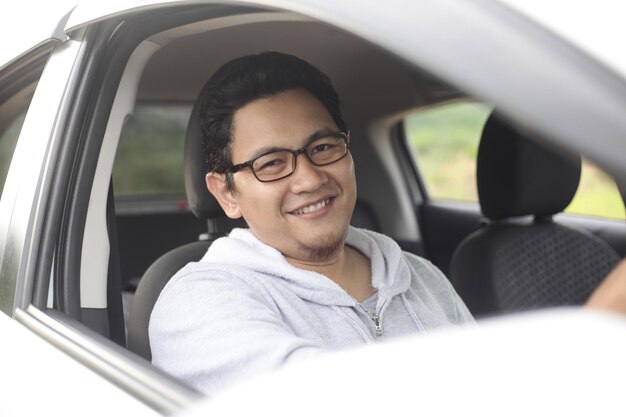 Photo happy asian driver in his car smiling having fun leisure in vacation trip car ride sharing concept