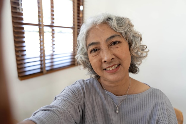 Photo happy asian elderly taking selfie photos with smartphone together in house portrait senior people smiling and looking at camera