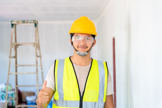 Felice ingegnere asiatico o concetto di affari di architettura e costruzione - uomo d'affari o architetto in casco al cantiere, edificio