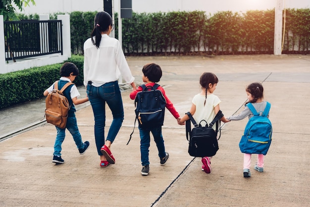 Happy Asian family children kid girl and boy kindergarten with backpack walking sidewalk going to school holding hand with mother mom, Back to school first day of semester concept