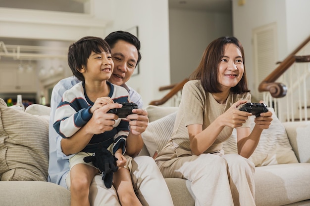 happy Asian family dad playing game with son and mom at home