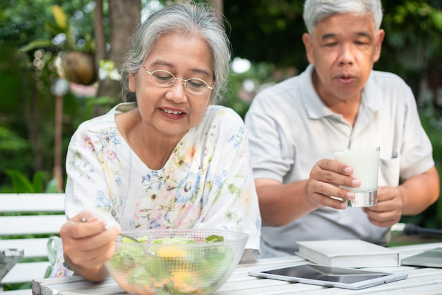 幸せなアジアの家族は裏庭で一緒に昼食を楽しんでいます夫はミルクの妻を養っています