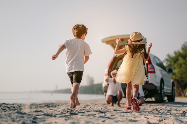 お気に入りの車でビーチ旅行を楽しんでいる幸せなアジアの家族両親と子供たちが旅行しています