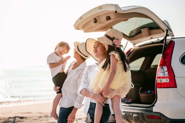 お気に入りの車でビーチ旅行を楽しんでいる幸せなアジアの家族両親と子供たちが旅行しています