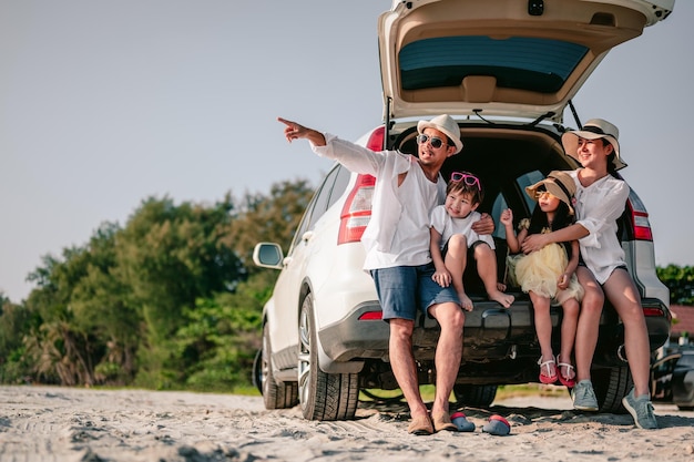 Happy asian family enjoying road trip with their favorite car\
parents and children are traveling the way to the sea or\
oceanholiday and travel family concept summer vacations