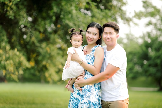 Happy Asian family father mother and little child daughter playing in the park enjoying the beautiful nature at sunset Happy family holidays concept