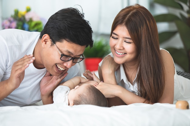 Happy asian family father mother with daughter playing on bed with smile face