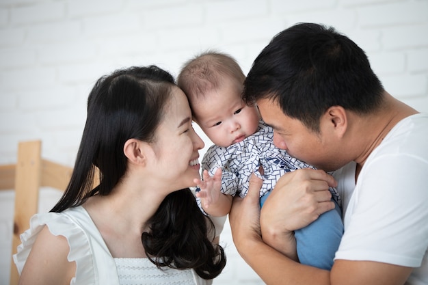 Madre felice asiatica del padre della famiglia con la figlia con il fronte di sorriso