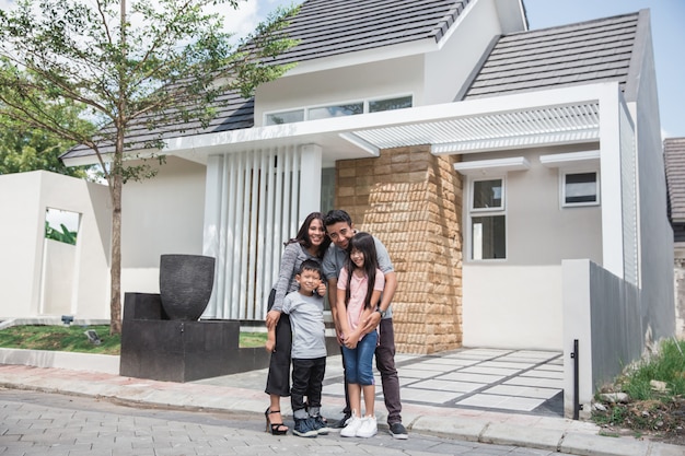 Happy asian family in front of their house