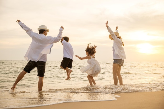 사진 행복한 아시아 가족은 일몰 시간에 휴일에 해변에서 함께 뛰어다니며 즐거운 시간을 보냅니다.