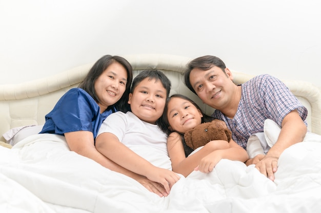 Happy Asian family lying and smile on a bed 