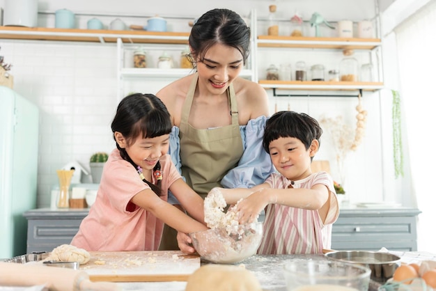 Famiglia asiatica felice che prepara la pasta e cuoce i biscotti in cucina a casa