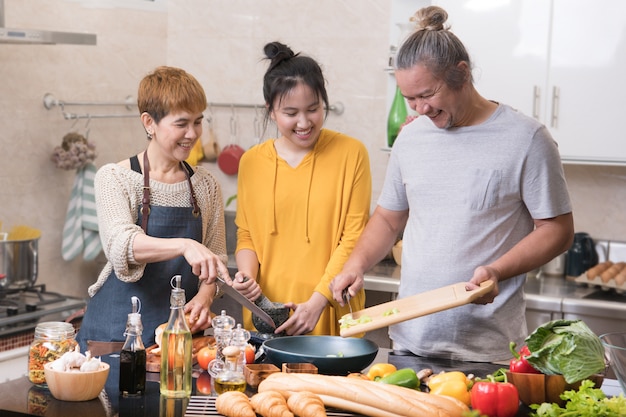 Photo happy asian family of mother father and daughter cooking in kitchen making healthy food together feeling fun