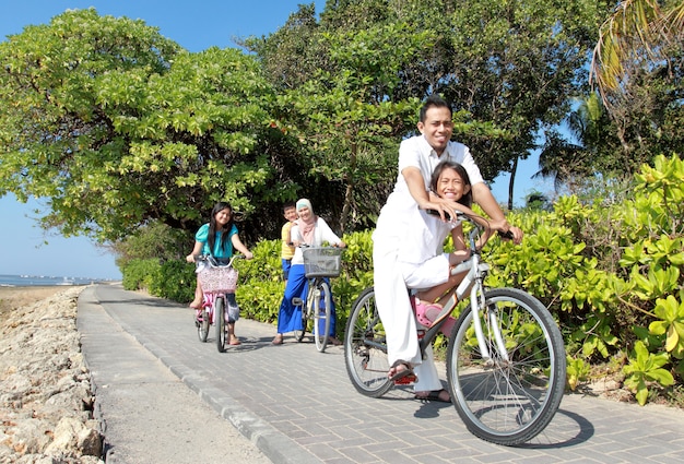 ビーチで美しい朝に自転車に乗って幸せなアジア家族