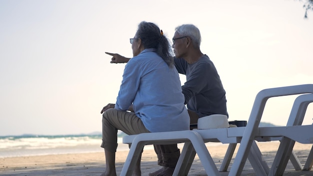 Photo happy asian family senior couple sitting on chairs with backs on beach travel vacation