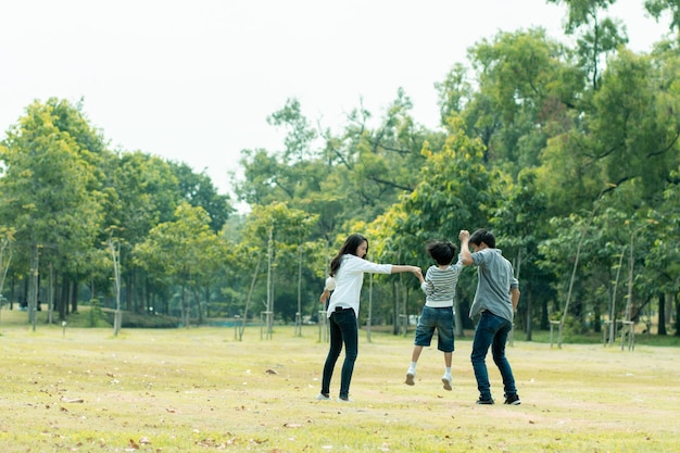 Счастливая азиатская семья проводит время вместе на улице в зеленой природе и парке отпуск родителей концепция