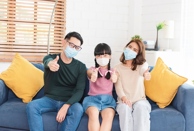 Happy Asian family wearing a mask to protect against viruses at home living room.