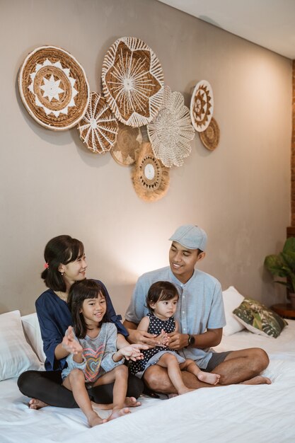 Happy asian family with two children spend their time together in the bedroom