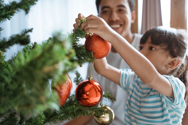 Happy Asian father and daughter decorating the Christmas tree