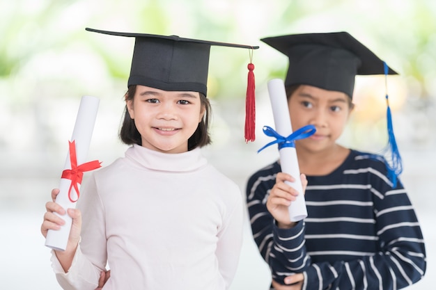 Happy asian female school kid graduates with a graduation cap\
hold a rolled certificate celebrate graduation. graduation\
celebration concept stock photo