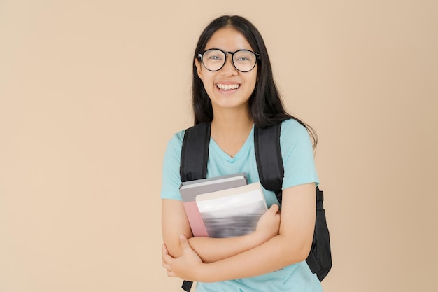 Una studentessa asiatica felice indossa occhiali e porta un libro