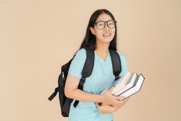 A happy Asian female student wears glasses and carries a book