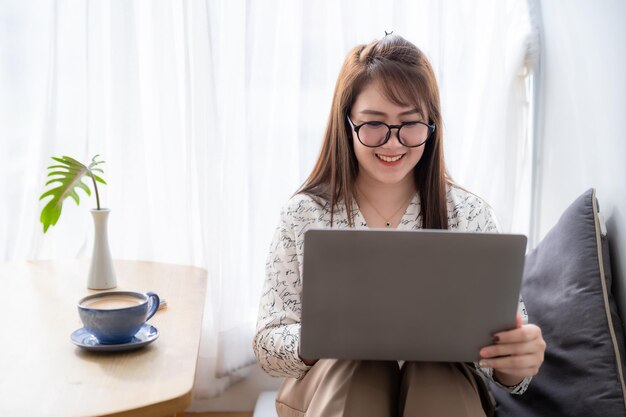 Happy of asian freelance people business female casual working with laptop computer with coffee cup and smartphone in coffee shop communication concept