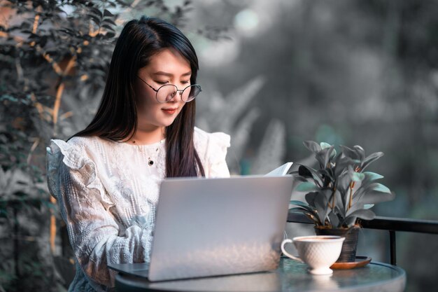 Happy of asian freelance people Businesswoman Taking written Notes to on notebook casual working with laptop computer with a coffee cup mug and smartphone at the cafe,Business Lifestyle