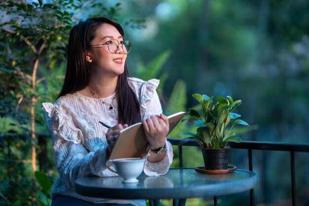 Happy of asian freelance people Businesswoman Taking written Notes to on notebook with a coffee cup mug felt like relaxing in coffee shop like the backgroundBusiness Lifestyle