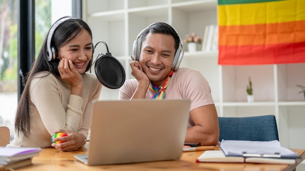 Happy Asian gay man enjoys talking reading comments online and recording podcast with his colleague