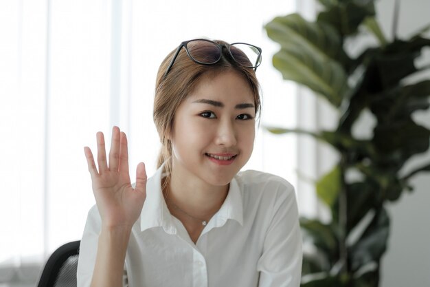 Happy asian girl blogger smiling face waving hand talking to webcam recording vlog, social media influencer streaming, making video call at home. Headshot portrait. Webcamera view.