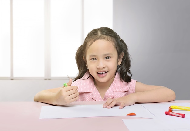 Happy asian girl drawing with crayon