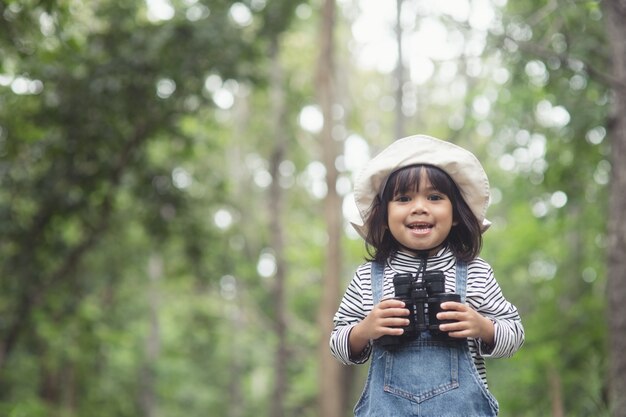 双眼鏡で旅の準備をしている幸せなアジアの女の子。