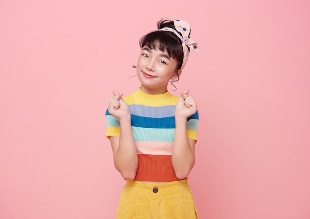 Happy asian girl hand showing mini heart gesture over pink background.