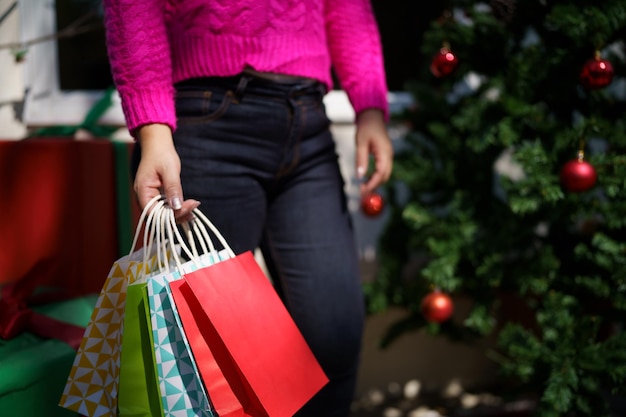 La ragazza asiatica felice tiene i sacchetti della spesa regalo di natale donna allegra con la vendita di natale capodanno inverno