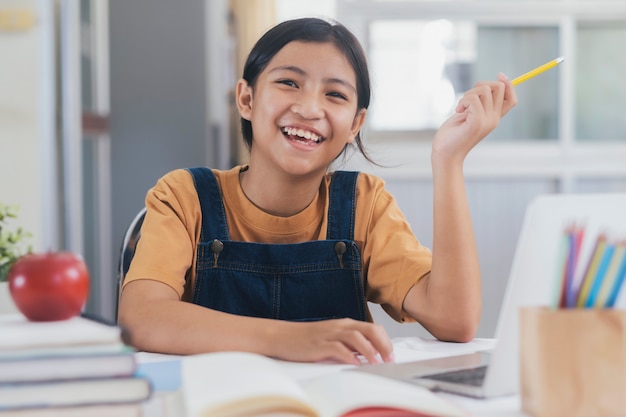 Ragazza asiatica felice che impara online a casa