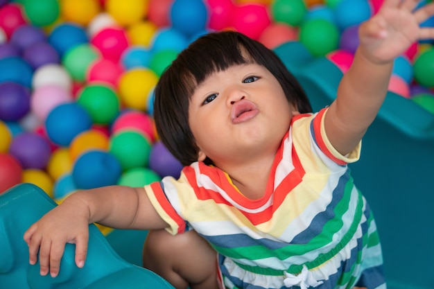 Happy asian girl (one and half years olds) playing little colorful balls in pool ball. the  playing is the best learning for children.