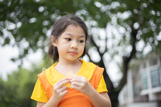 Happy asian girl in orange dress eating jelly candy
