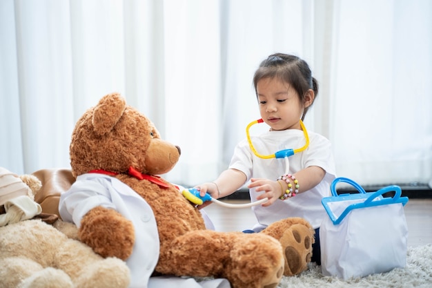 A happy asian girl playing doctor or nurse listening a stethoscope to toy.