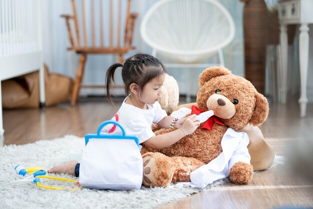 A happy asian girl playing doctor or nurse listening a stethoscope to toy.