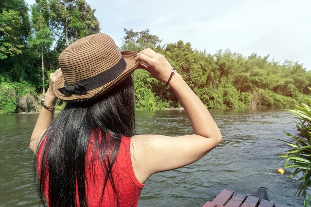 Happy Asian girl red shirt and brown hat on the river in nature background