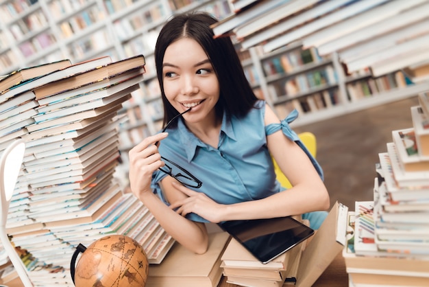 Photo happy asian girl sitting at table surrounded by books.