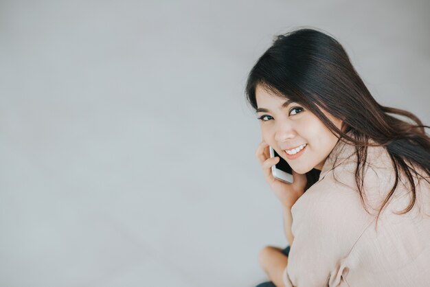 スマートフォン屋内を使用している幸せなアジアの女